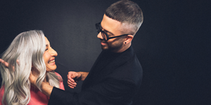 white woman with long blonde hair, which stands in front of a clean grey background looking into the camera